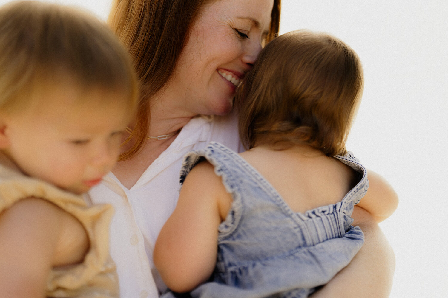 A mother with her eyes closed, breathing in her child as she holds them close
